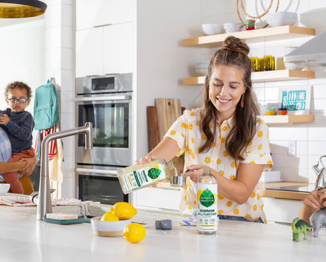 Family in kitchen, adult using cleaner concentrate, children interacting with each other