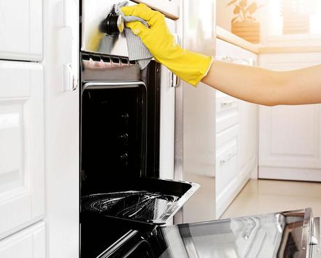 Person cleaning oven with gloves
