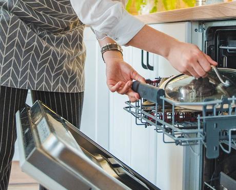 close up image of hands putting dishes in dishwasher