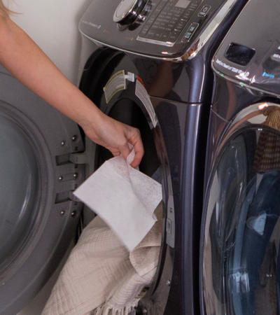Person adding fabric softener sheet to dryer