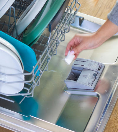 photo of person's hand adding auto dish pack to the dishwasher