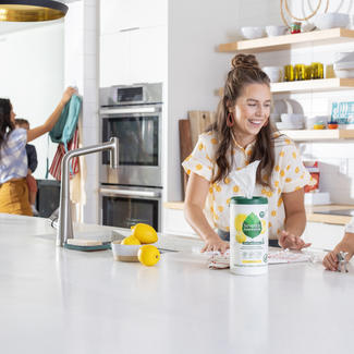 Adults and Children cleaning kitchen - Seventh Generation Multi-Surface Wipes canister on countertop.